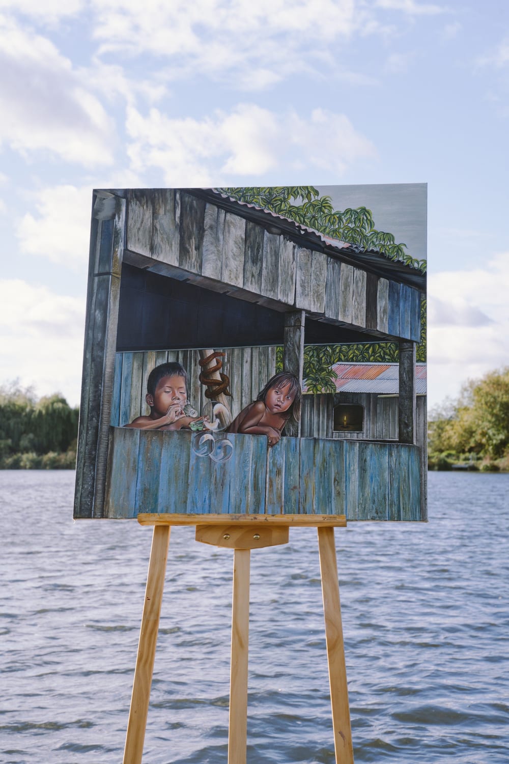 Inocencia on an easel standing in the water under a cloudy sky.