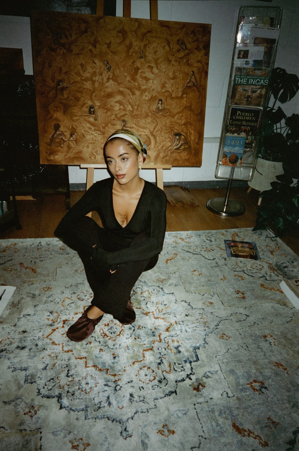 Valeria crouching on a patterned rug in front of Pachamama.