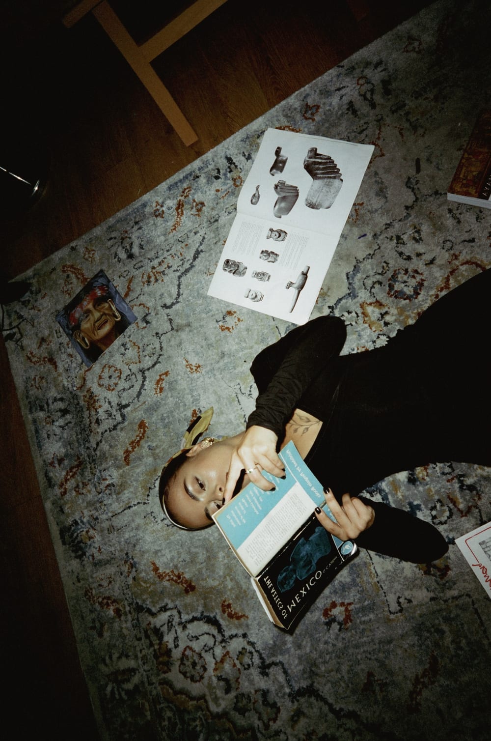 Valeria lying on a rug with a book, seen from above.
